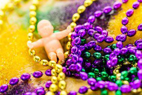 A king cake with beads and a baby from New Orleans, LA